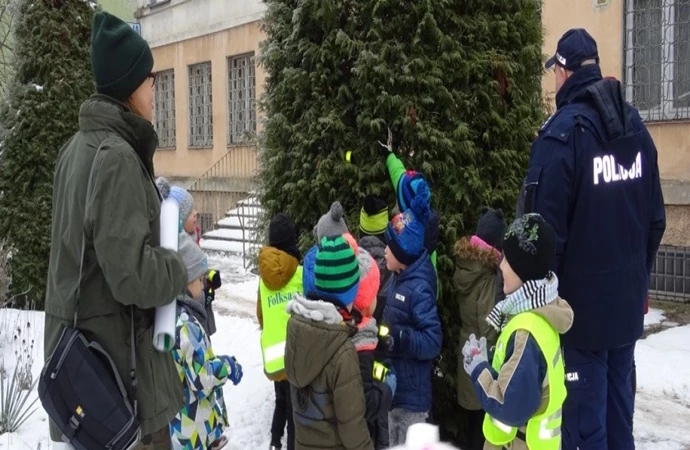 {Piscy policjanci zaprosili tamtejsze przedszkolaki do wspólnego rozbierania odblaskowej choinki.}